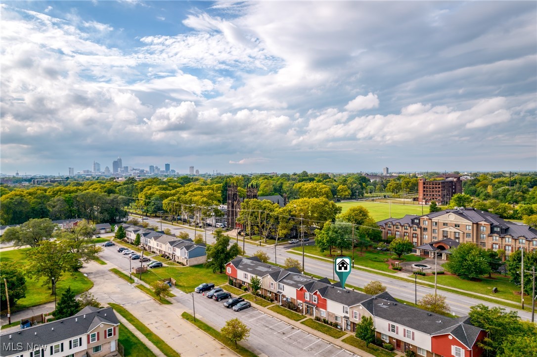 Aerial neighborhood view with attached homes, leafy trees, and the Cleveland skyline in the distance.