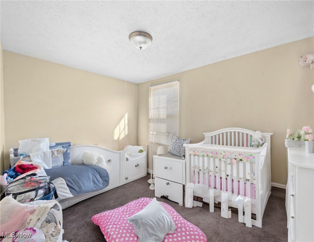 Nursery with a white crib decorated with pastel flowers beside a white toddler bed with blue bedding.