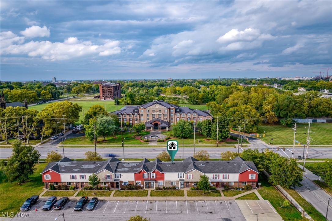 Aerial view of attached red-and-beige homes with a parking lot and landscaped grounds nearby.