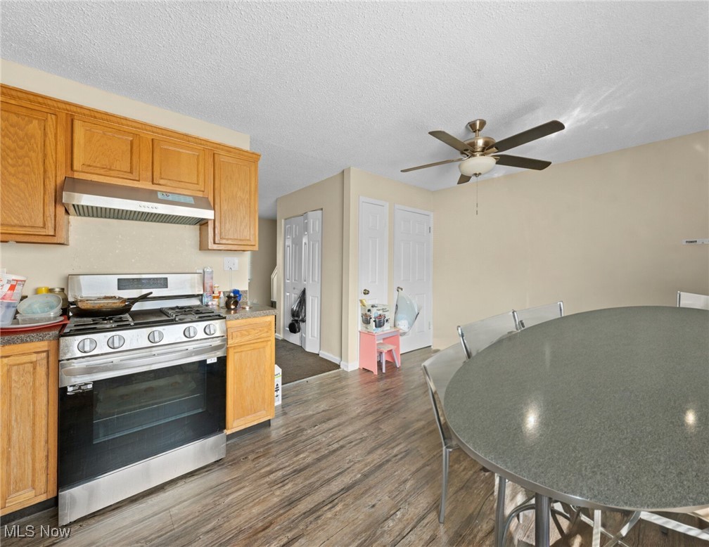 Kitchen and dining area with wood cabinets, a stainless steel gas range, and a large round table.