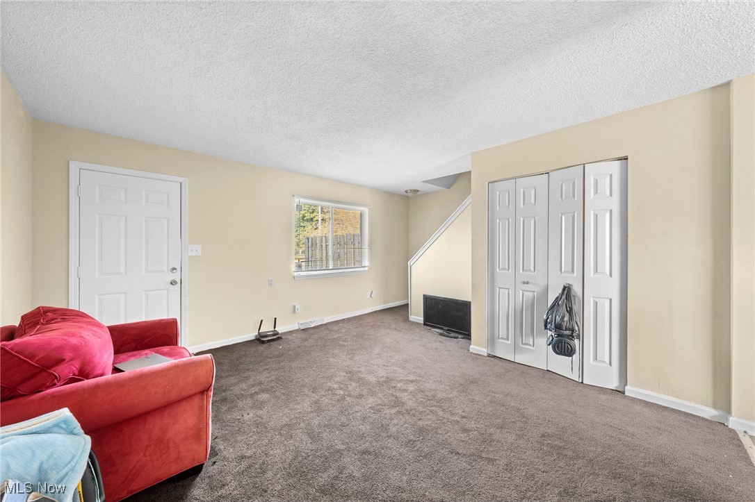 Living room with brown carpet, a red sofa, and white closet doors.