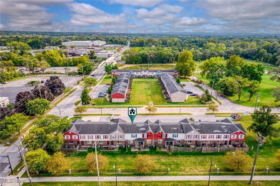 Aerial view of a red-and-white multi-unit residential building with a lawn and courtyard.