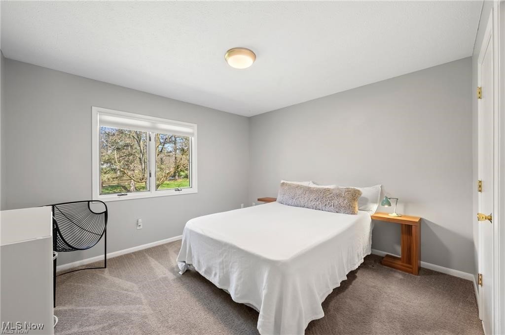 Bedroom with a white-covered bed, gray walls, and a window overlooking trees.