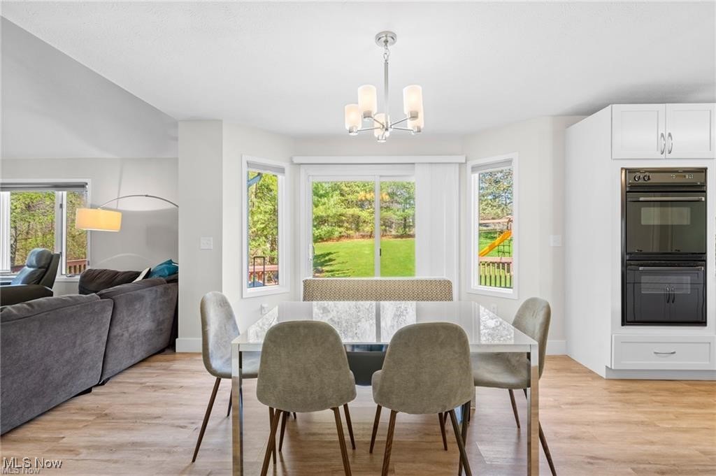 Dining room with a marble-look table, upholstered chairs, and windows overlooking the backyard.
