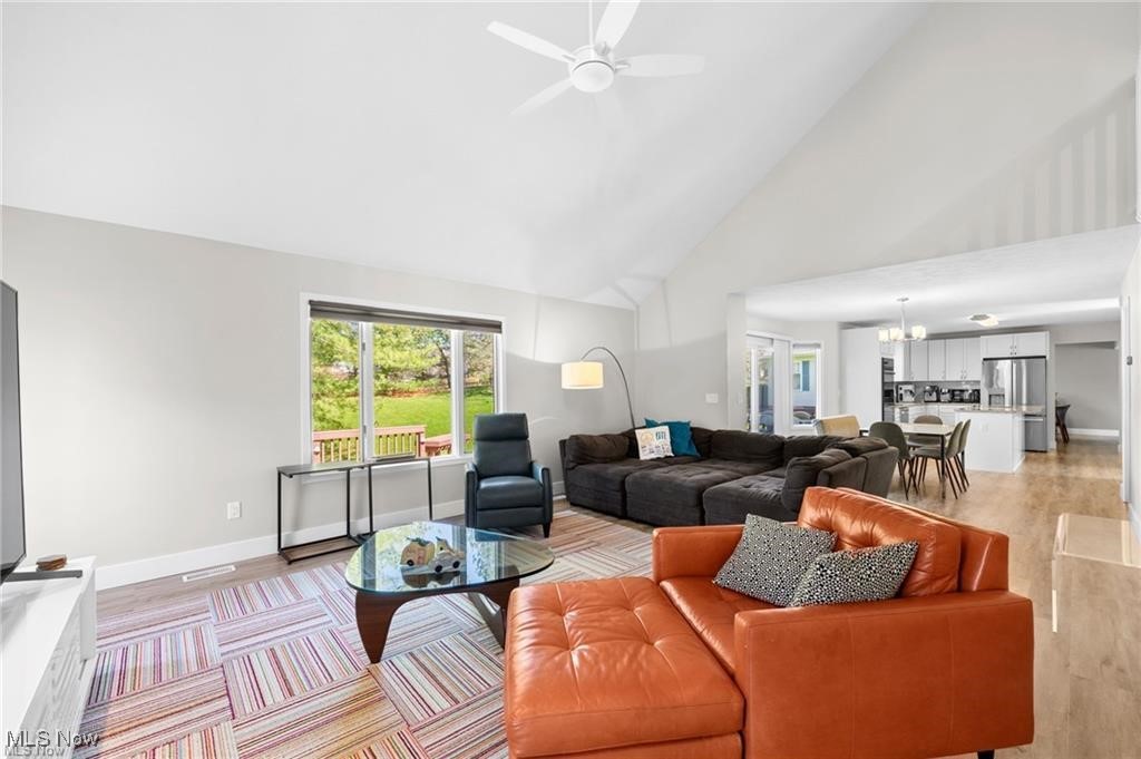 Furnished living room with vaulted ceiling, orange leather sectional, and an open view into the kitchen.
