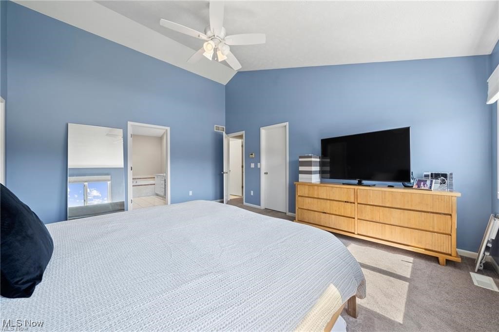 Bedroom with blue walls, a vaulted ceiling, a large bed, and a wooden dresser with a television.