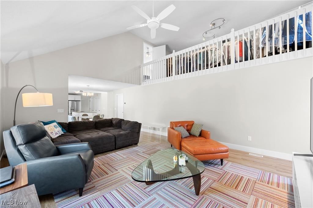 Living room with a vaulted ceiling, loft railing, dark sectional, orange chaise, and colorful geometric rug.