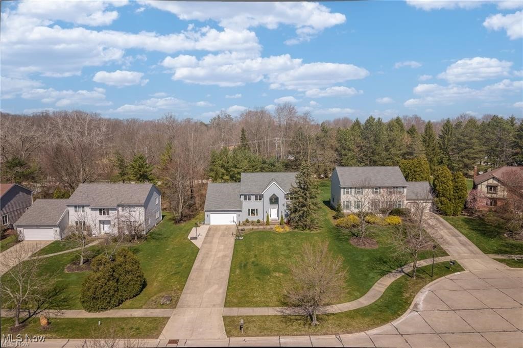 Aerial view of a two-story white home with an attached garage and long driveway.