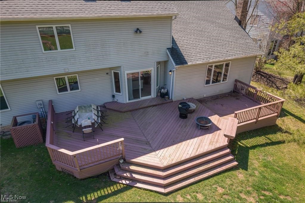 Rear of a two-story house with a large multi-level deck, wide steps, and a fire pit.