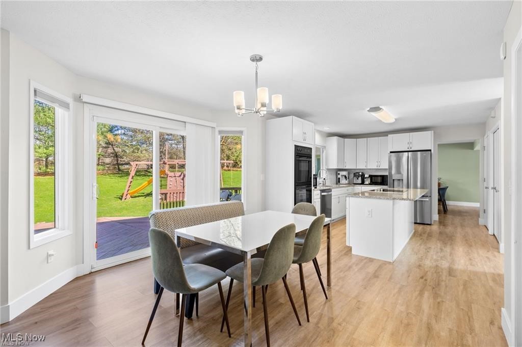 Open dining area and kitchen with white cabinetry, a central island, and sliding doors to the backyard.