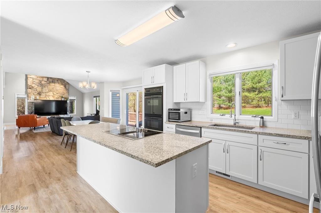 Open kitchen with a granite island, white cabinets, and a view into the living room.