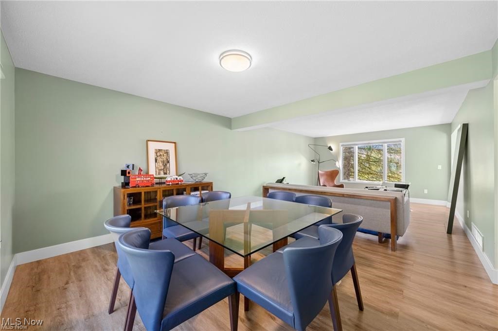 Dining and sitting area with a glass-top table, blue chairs, and a sofa beside a window.