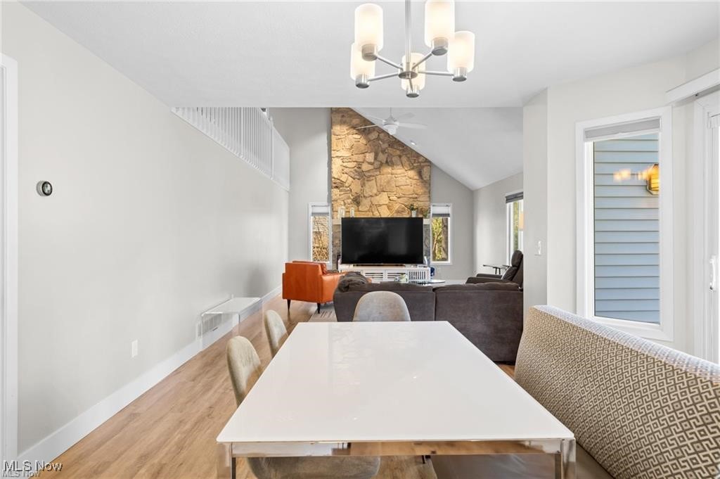 Dining area opens to a living room with a stone fireplace and vaulted ceiling.