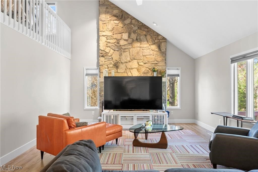 Living room with a tall stone fireplace, vaulted ceiling, and leather seating.