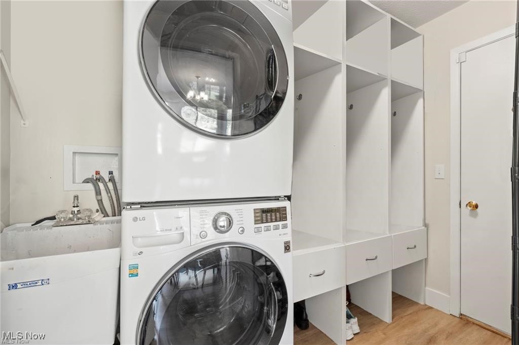 Laundry room with stacked washer and dryer, utility sink, and built-in storage cabinets.