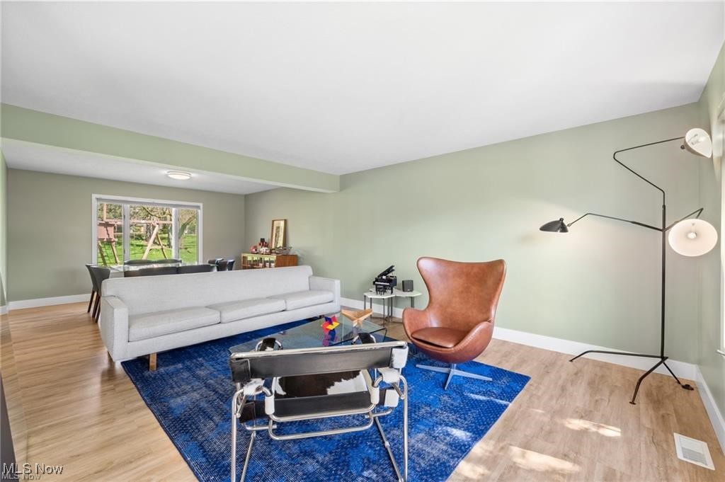 Living room with a white sofa, leather lounge chair, and blue rug beside large windows.