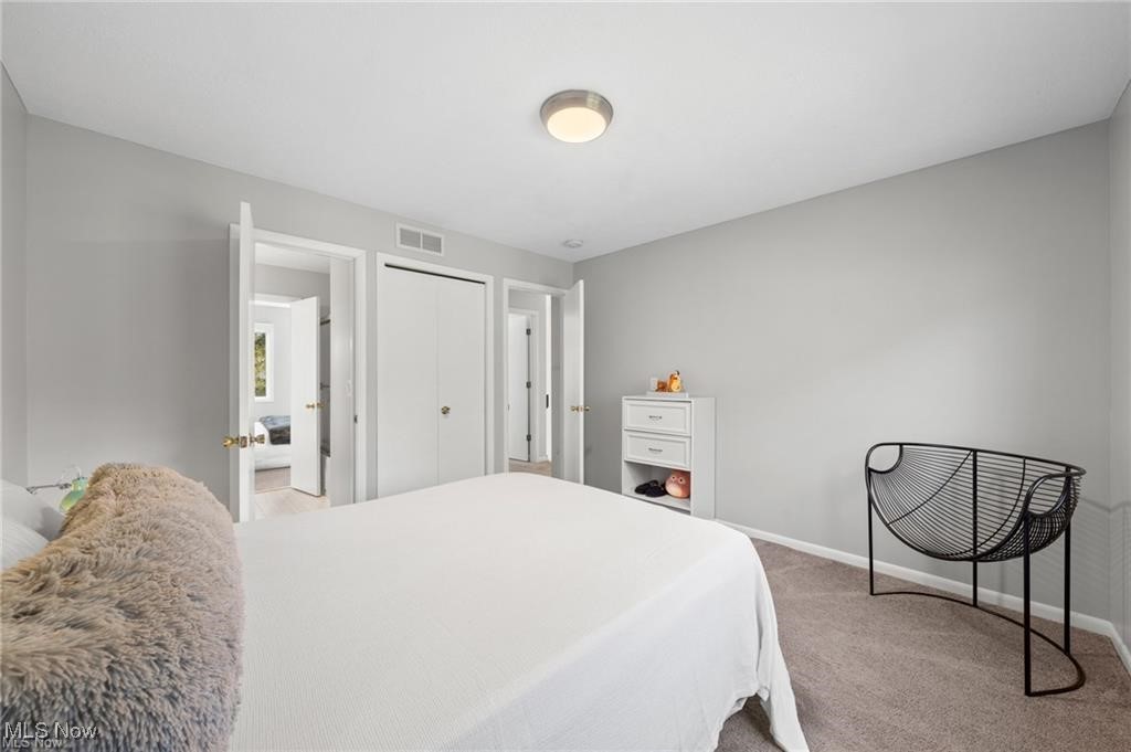 Bedroom with a white bed, gray walls, and a black wire-frame chair.