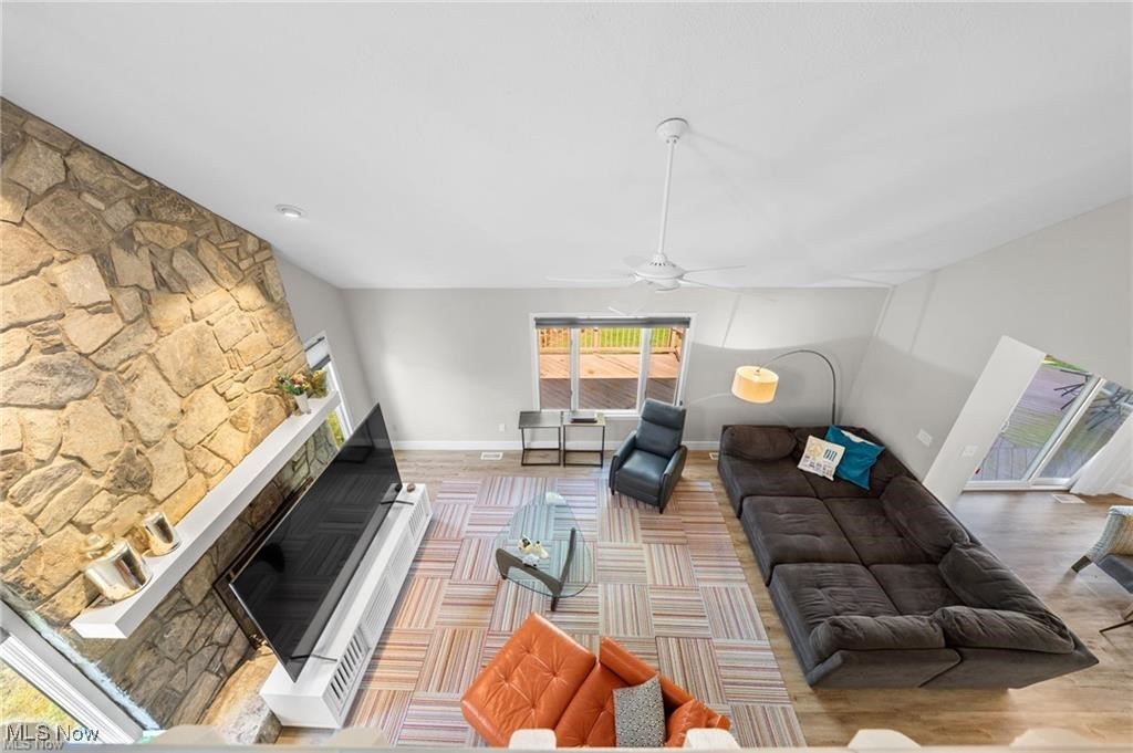 Living room with a stone fireplace, large sectional sofa, colorful rug, and sliding doors to a deck.