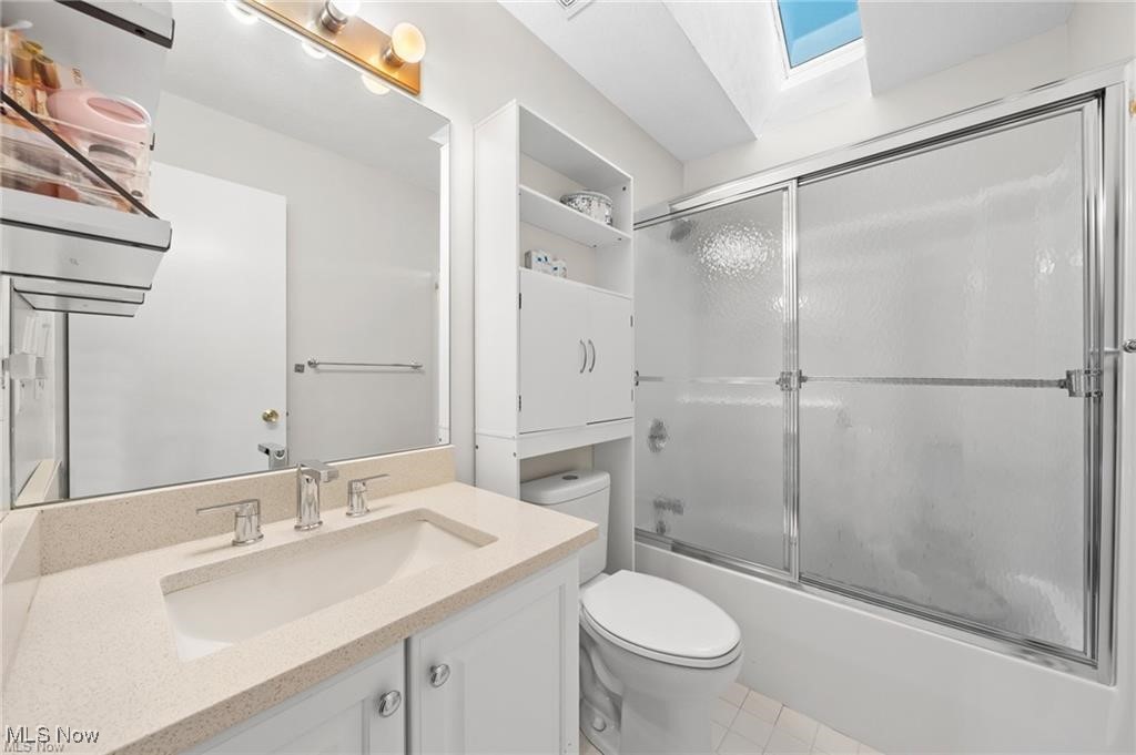 Bathroom with a white vanity, mirrored wall, and bathtub behind frosted glass doors.