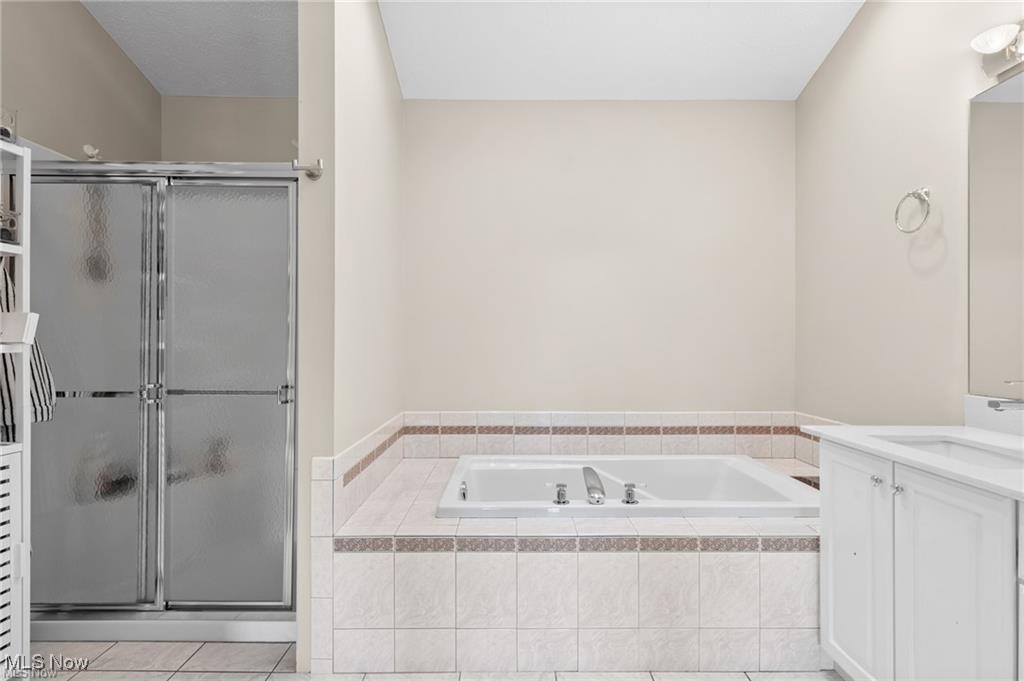 Bathroom with a built-in jetted tub, tiled surround, and frosted-glass shower.