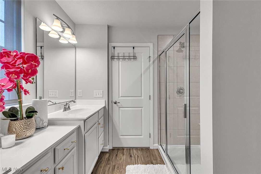 Bathroom with a long white double vanity, glass shower, and pink orchids on the counter.