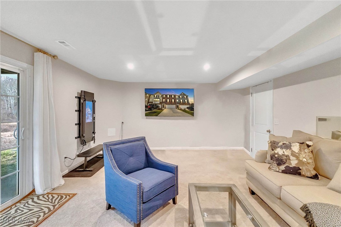 Living room with blue armchair, cream sectional, and sliding glass door overlooking leafless trees.