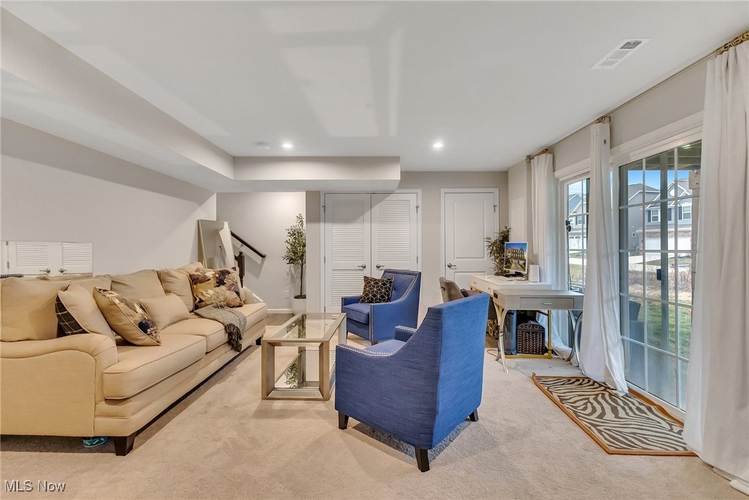 Furnished living room with a beige sofa, blue armchairs, and large windows.
