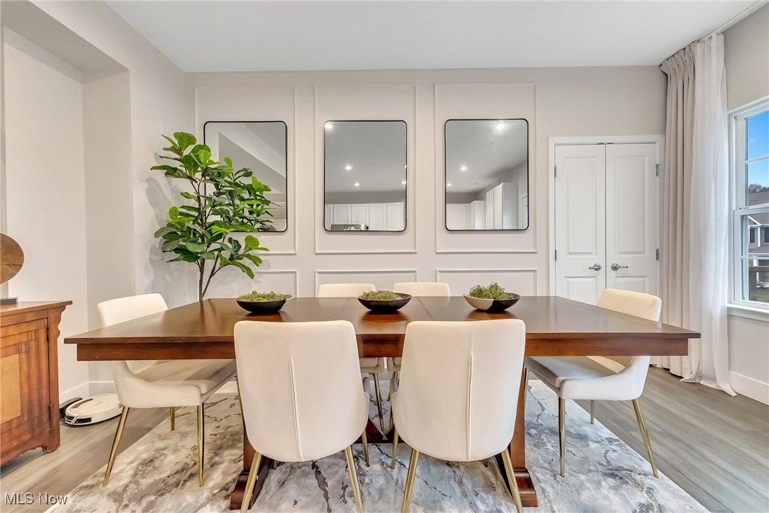 Dining room with a long wood table, white chairs, paneled walls, and three mirrors.