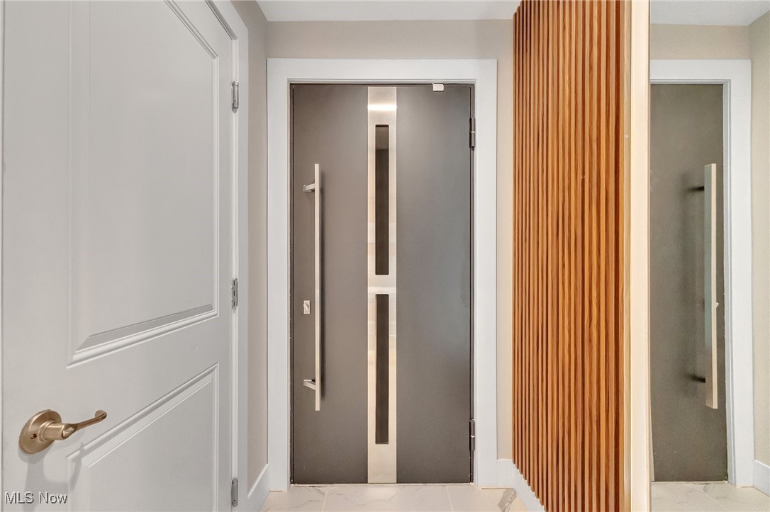 Modern entry foyer with a dark front door, brass hardware, and a vertical wood-slat partition.