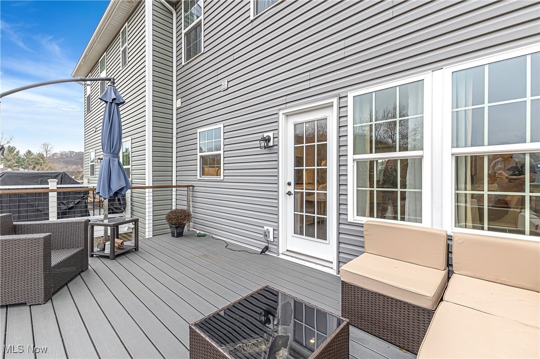 Gray composite deck with wicker patio seating, a glass-top table, and a closed umbrella.