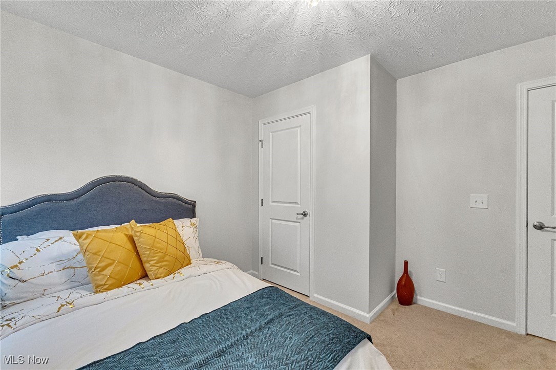 Staged bedroom with a blue headboard, mustard pillows, and a teal bedspread.