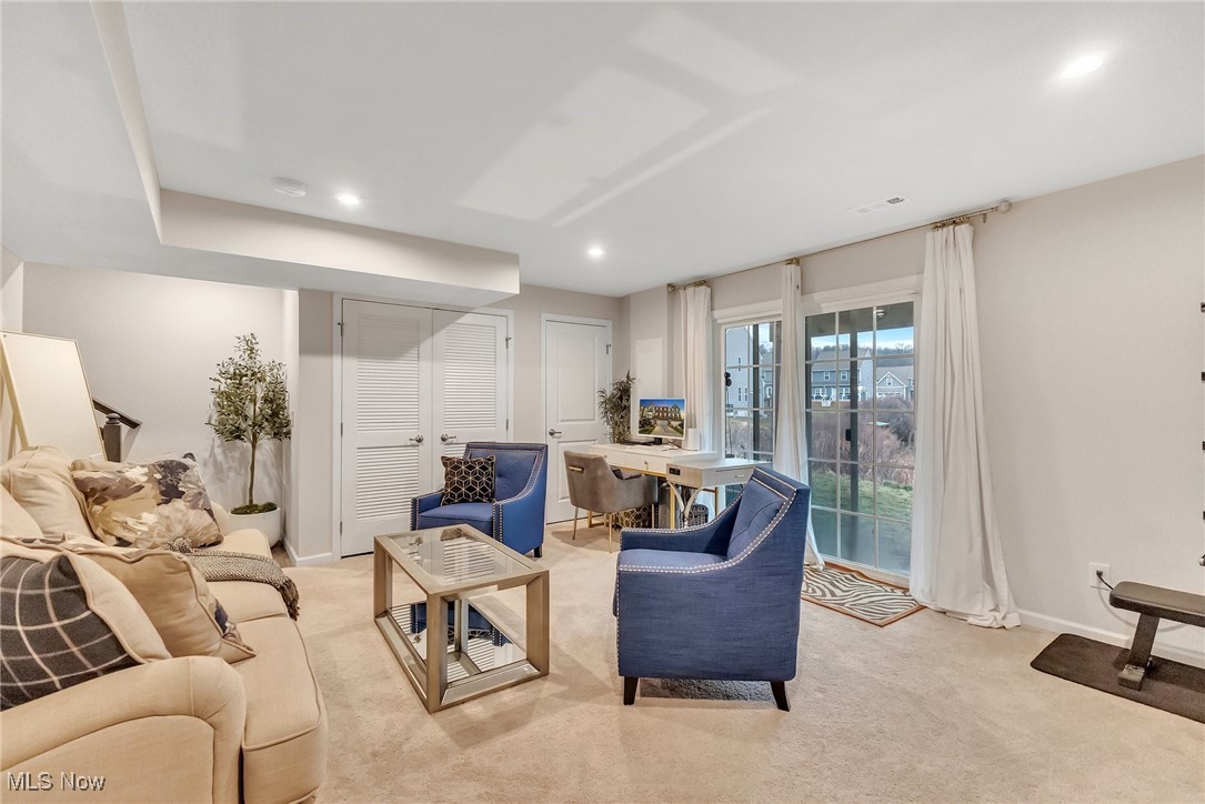Staged living room with blue armchairs and a desk beside glass doors to the yard.