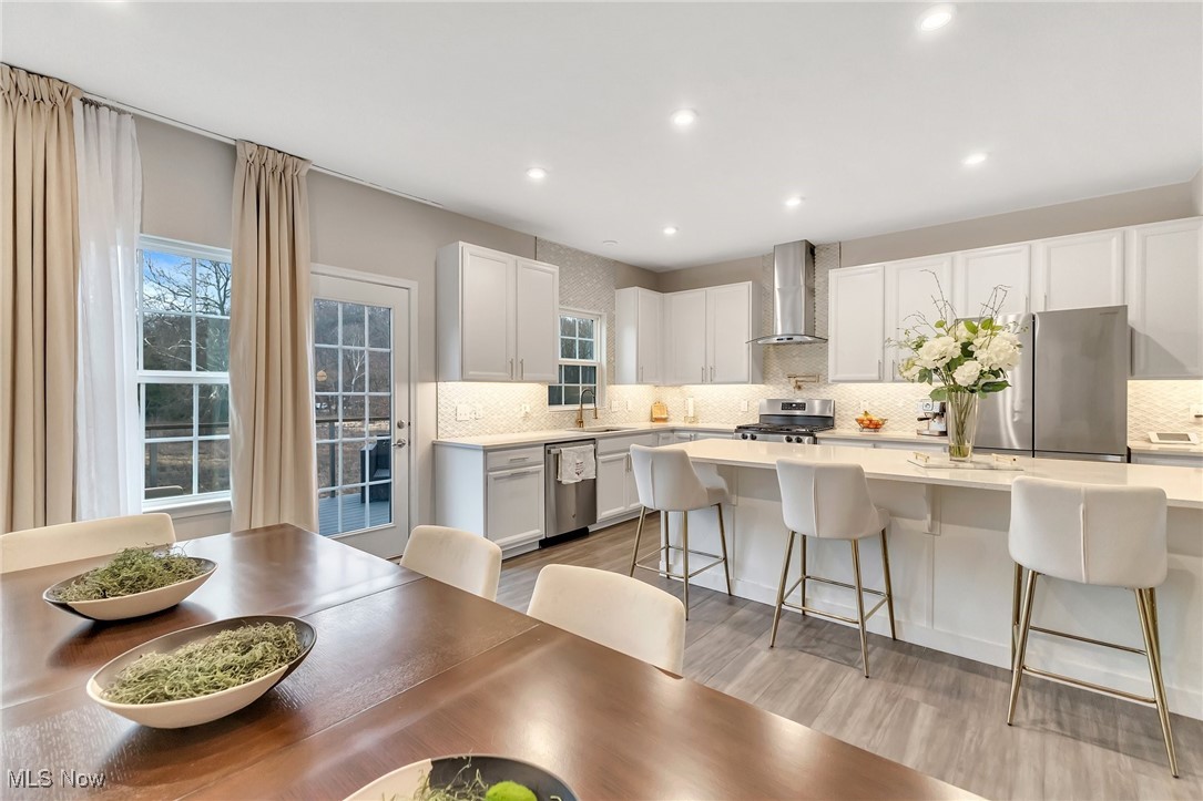 Open-plan kitchen and dining area with white cabinetry, a breakfast island, and a dark wood table.