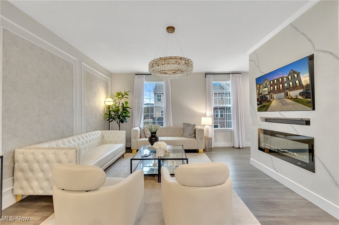 Living room with cream seating, a glass coffee table, and a modern fireplace beneath a wall-mounted television.