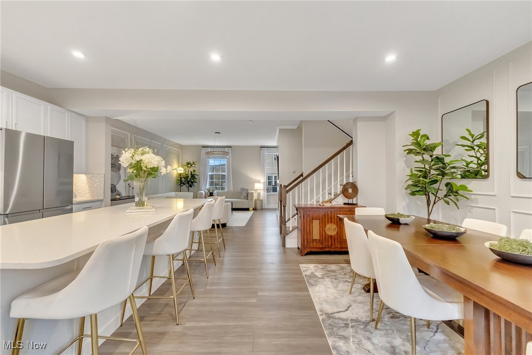 Open-plan kitchen and dining area with a large quartz island, white stools, and a wood table.
