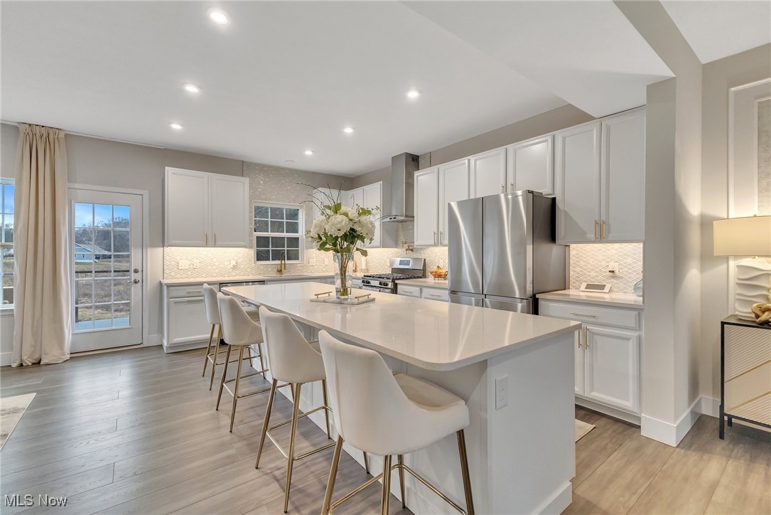 Updated kitchen with a large white island, four bar stools, and stainless steel appliances.