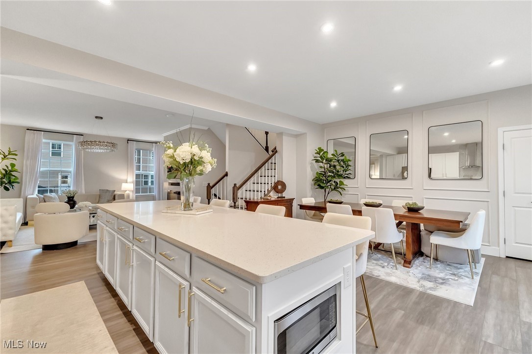 Open-plan kitchen with a large white island, adjoining dining table, and living room beyond.