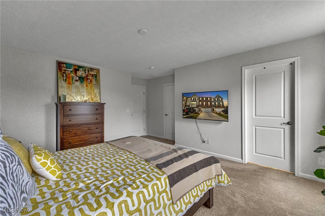 Bedroom with yellow geometric bedding, a wooden dresser, and a wall-mounted television.