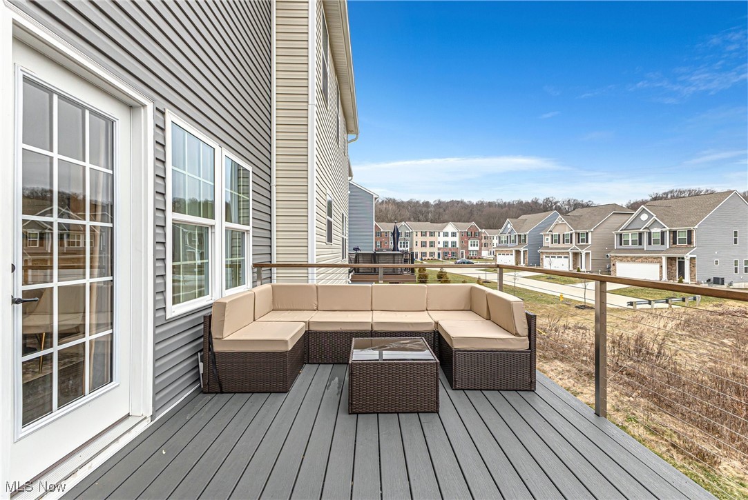 Furnished deck with a beige-cushioned sectional and neighborhood homes beyond the railing.