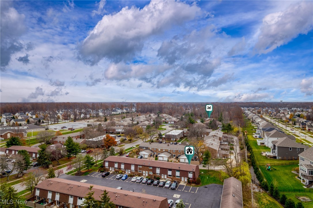Aerial view of a residential neighborhood with rows of homes and parking areas beneath a dramatic cloudy sky.