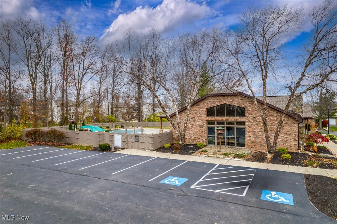 Brick building beside a fenced swimming pool and accessible parking.