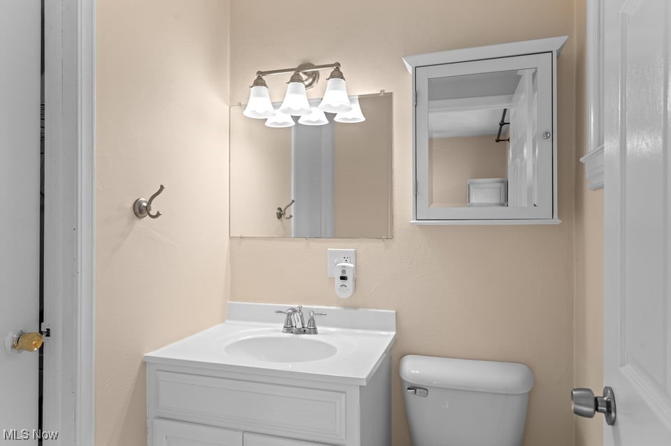 Bathroom with a white vanity, sink, mirror, and toilet.