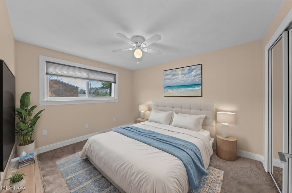 Furnished bedroom with a white bed, blue throw, beach artwork, and sliding glass doors.