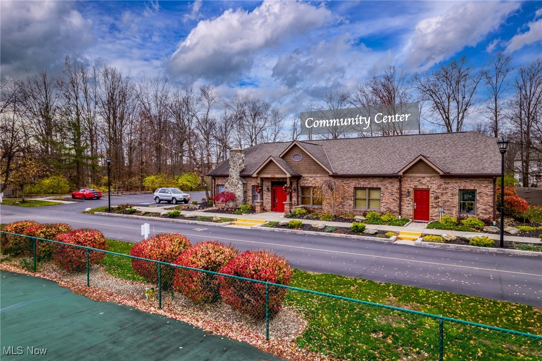 Brick community center with red doors, stone chimney, and landscaped grounds.
