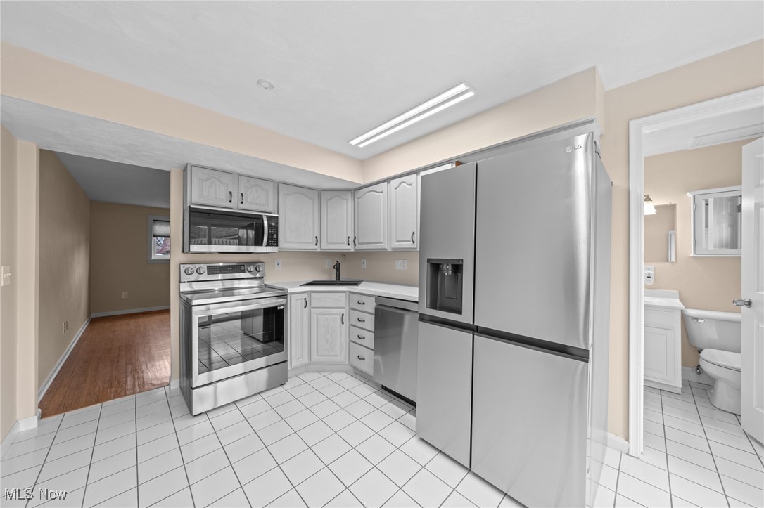 Kitchen with white cabinets, stainless steel appliances, and a tiled floor.