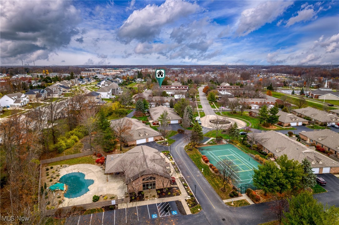 Aerial neighborhood view with a home marker, backyard pool, and tennis court.