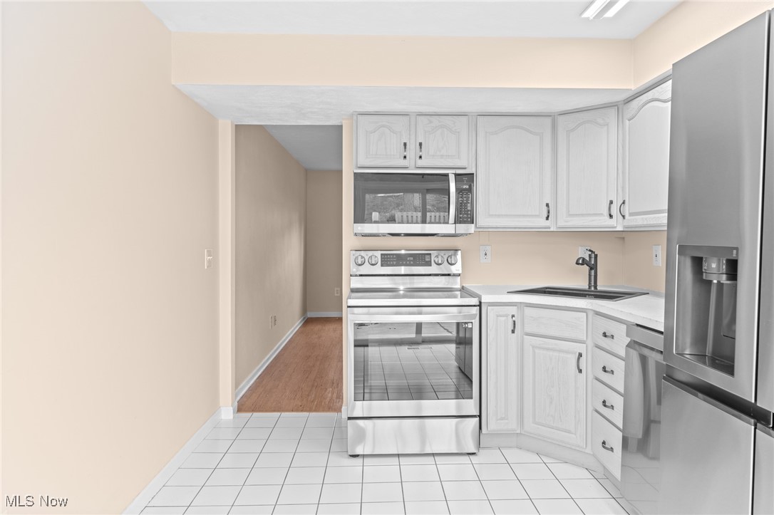 Kitchen with white cabinets, stainless steel appliances, and a tiled floor.