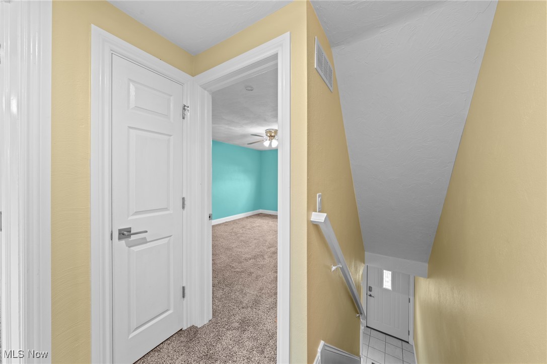 Upstairs hallway and stairwell beside an open door to a turquoise bedroom.