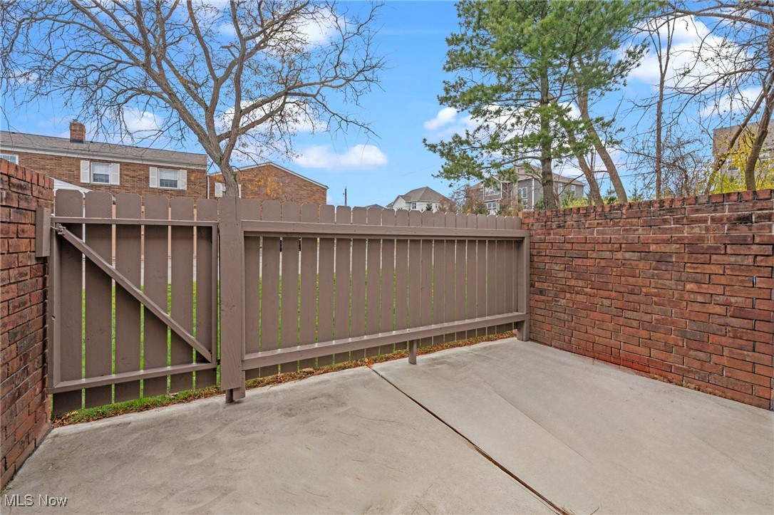 Paved patio enclosed by brick walls, with a brown wooden gate.