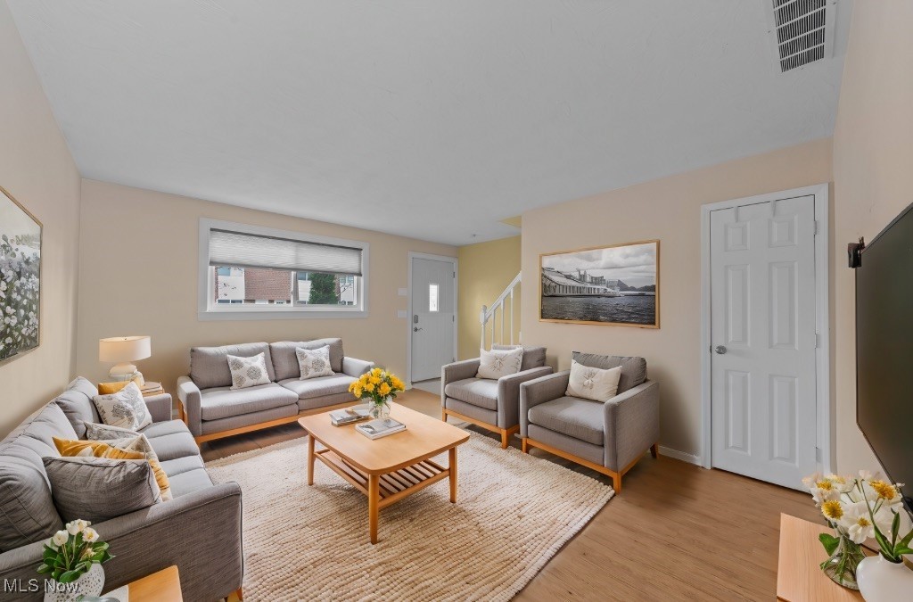 Living room with gray seating, a cream rug, and a staircase behind the sofas.